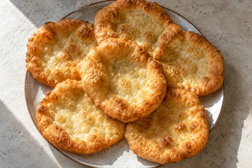 Hat kisebb, aranybarna, instant élesztővel készült lángos egy egyszerű tányéron